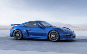 藍色保時捷Cayman GT4跑車，紅色制動器，停在日落時分山邊的混凝土上。 — 藍色 壁紙