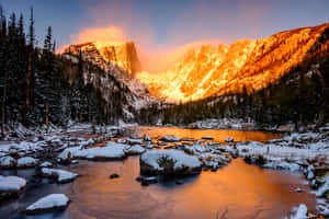 被金色夕陽照耀的雪山山峰倒映在平靜的河流中。 — MacBook Air M2 壁紙