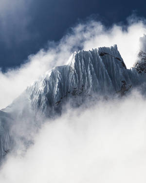 積雪山峰在深藍色天空的雲層之上聳立