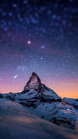 白雪覆蓋的馬特洪峰在紫色和橙色色調的星空暮色天空下。