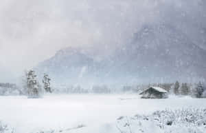冬季風景中的雪中小屋，有山脈和飄雪。