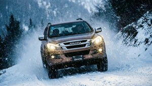 棕色五十鈴卡車在冬季暴風雪中行駛於積雪森林。