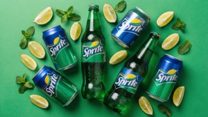 Sprite 汽水罐和瓶子被青檸角和薄荷葉包圍在綠色背景上。