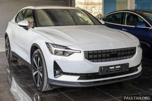 白色Polestar 2電動車在展廳中展示，地面為深色瓷磚，背景有一輛藍色汽車。 — 汽車 壁紙