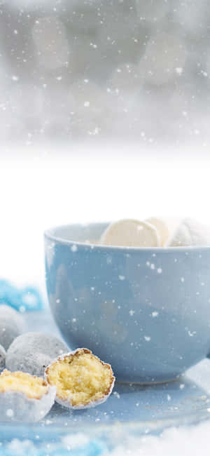 藍色碗裝滿撒滿雪的糕點，其中一個在飄雪中破開。 — iPhone 12 mini 壁紙
