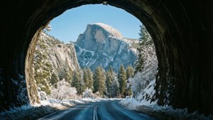 積雪的道路從隧道中出現，進入山區森林，半圓頂在望