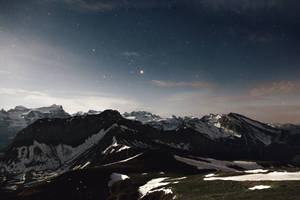 在繁星點點的夜空下，白雪覆蓋的山脈與閃耀的行星。 — 冬天桌面 壁紙