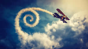 復古雙翼飛機飛行並在多雲的天空中留下螺旋煙霧痕跡