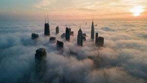 日出時從雲層中浮現的城市天際線 — 城市景觀 壁紙
