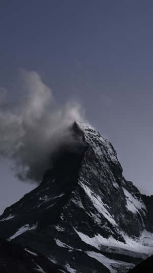 一座白雪覆蓋的山峰，雲霧在山頂周圍旋轉。