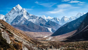 積雪的山峰在明亮的藍天下，從岩石山谷中拔地而起。