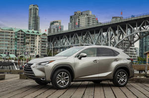 銀色Lexus NX SUV在木碼頭上，背後有城市橋樑和天際線。