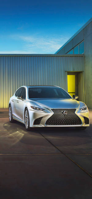 銀色Lexus轎車停在一座帶有黃色門的現代建築旁，藍天之下。