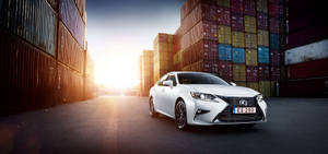 白色Lexus ES 200轎車停放在堆疊的貨運集裝箱之間，夕陽西下。