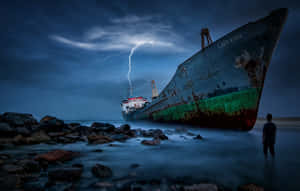 一個人站在水中，面對著暴風雨和閃電下的大型沉船。