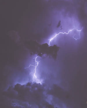 紫色閃電在夜間穿過黑暗的暴風雲閃爍。
