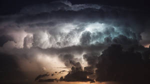 夜間，戲劇性的風暴雲被閃電照亮，映襯著發光的橙色地平線。