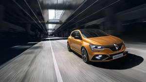 橙色雷諾 Mégane R.S. 在黑暗隧道中疾馳，帶有動態模糊。