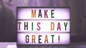 一個彩色燈箱標誌，上面寫著「MAKE THIS DAY GREAT!」