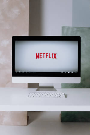 一部現代電腦在潔白的桌子上顯示Netflix標誌。