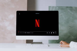 手使用滑鼠在現代 iMac 電腦上串流 Netflix。