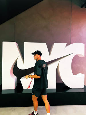 身穿Nike服裝的年輕男子在室內大型NYC標誌裝置旁擺姿勢。