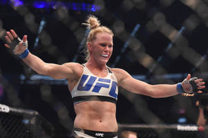 女性MMA拳手在UFC八角籠中舉起雙臂慶祝勝利。 — 冠軍 壁紙