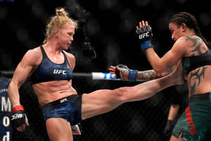 籠中的兩名女性MMA拳手，一人踢向另一人，後者阻擋。 — 拳擊 壁紙