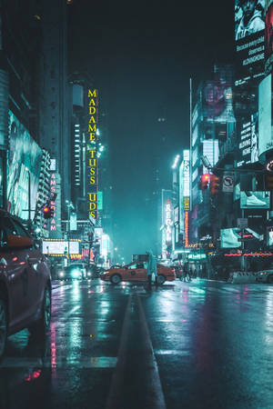 夜晚霓虹燈照亮的城市街道，濕漉漉的人行道反射燈光和出租車。