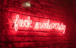 夜間磚牆上寫著「fuck mediocrity」的紅色霓虹燈牌。