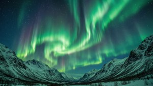 綠色和紫色北極光照亮星空下白雪覆蓋的山峰。