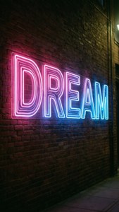 夜間磚牆上寫著DREAM的霓虹燈牌。 — 漸變色 壁紙