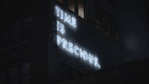 夜晚黑暗建築上寫著 time is precious 的霓虹燈牌。 — 霓虹 壁紙