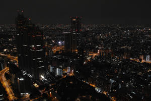 密集城市區域的夜間空中照片，建築物和道路燈火通明。