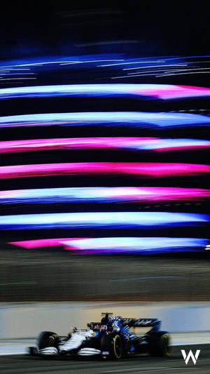 一級方程式賽車在夜間高速行駛，帶有霓虹燈光條紋。 — 汽車 壁紙