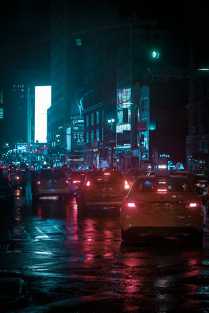夜晚的城市街道，濕漉漉的路面反射霓虹燈光和行駛中的汽車。 — 霓虹城市 壁紙