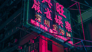 霓虹燈在夜晚用粉紅色和藍綠色的燈光照亮城市建築。 — 香港 壁紙