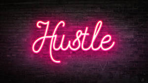 深色磚牆上寫著 'Hustle' 的粉紅色霓虹燈牌。