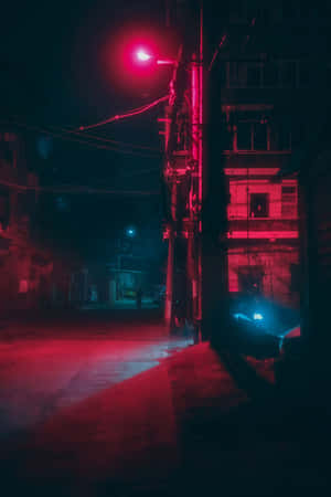 夜晚紅光照亮的小巷，有建築物和架空電線。