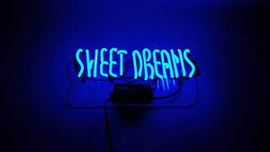 深色牆壁上寫著 sweet dreams 的藍色霓虹燈牌。