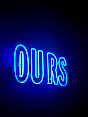 藍色霓虹燈牌顯示「OURS」，在深色牆壁上發光。