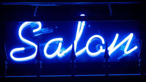 藍色霓虹燈牌，上面寫著 Salon，在黑暗中帶有骰子倒影。