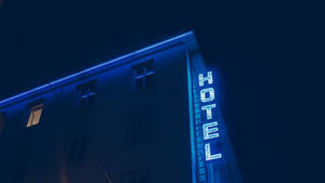 藍色霓虹酒店標誌在夜晚的建築物上發光。