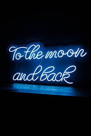 藍色霓虹燈牌，上面寫着 'To the moon and back'，掛在深色牆上。 — 霓虹藍色美學 壁紙
