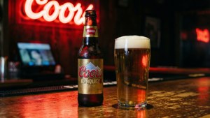 紅色霓虹燈下酒吧上的Coors Banquet啤酒瓶和玻璃杯。