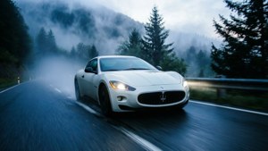 白色跑車在黃昏時分快速行駛於霧氣瀰漫的山路上。