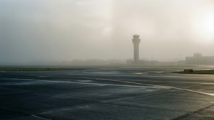 機場停機坪籠罩在霧中，遠處可見控制塔