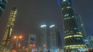 夜晚霧氣瀰漫的城市天際線，閃爍的高樓大廈和街燈。 — 夜空 壁紙