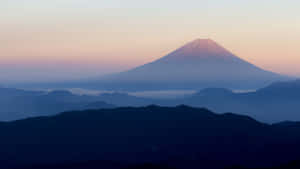 黎明時分的富士山，層疊山巒輪廓之上有粉紅色和藍色的天空。 — 日本 壁紙