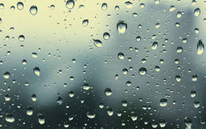窗戶上的雨滴，背景是模糊的天空。